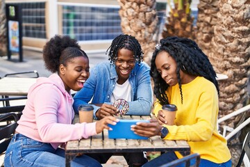 African american friends having breakfast watching video on touchpad at coffee shop terrace