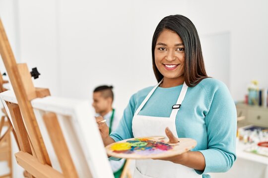 Young latin painter couple smiling happy painting at art studio