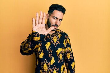 Young hispanic man wearing casual shirt doing stop sing with palm of the hand. warning expression...