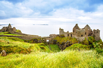 Fototapeta na wymiar Ruins of Dunluce Castle, Antrim, Northern Ireland during sunny day with semi cloudy sky. Irish ancient castle near Wild Atlantic Way.