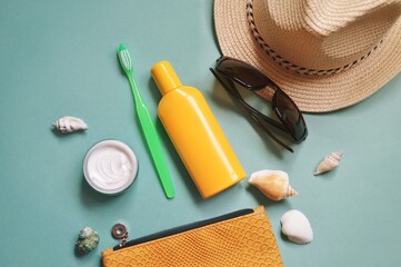 Top view photography the contents of a beautician for travel. Moisturizing  cream, green toothbrush, sunscreen bottle, sun hat, sunglasses and sea shells