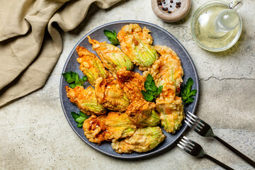 Italian appetizer. Fried in a batter Zucchini Flowers stuffed with ricotta cheese and parsley. Roasted courgette or pumpkin flowers. Fiori di zucca in pastella. Stone background. - obrazy, fototapety, plakaty