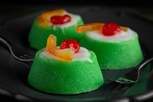 Close up of Italian dessert Cassata siciliana. Typical sicilian cheese cake made with almond, sponge cake, ricotta cheese and candied fruit, with shell of green marzipan icing. Dark background.