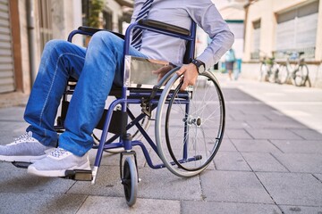 Middle age hispanic man wearing business clothes sitting on wheelchair at street