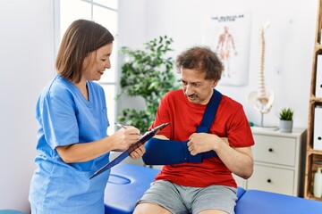 Middle age man and woman wearing physiotherapy uniform having rehab session at physiotherapy clinic