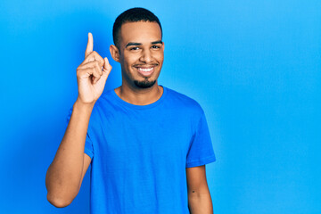 Young african american man wearing casual blue t shirt pointing finger up with successful idea....