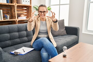 Fototapeta premium Young woman working at consultation office shouting frustrated with rage, hands trying to strangle, yelling mad