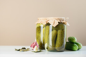 Canned vegetables cucumber in glass jars on beige background. Homemade harvest fall preparations. Close up. Copy space.