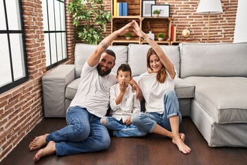 Family of three doing house shape with arms covering mouth with hand, shocked and afraid for mistake. surprised expression