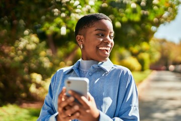 Young african american woman smiling happy using smartphone at the city