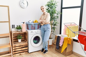 Young caucasian woman smiling confident standing with arms crossed gesture at laundry room
