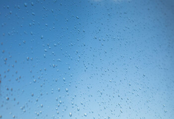 Selective focus rain drops on the window glass against blue sky background
