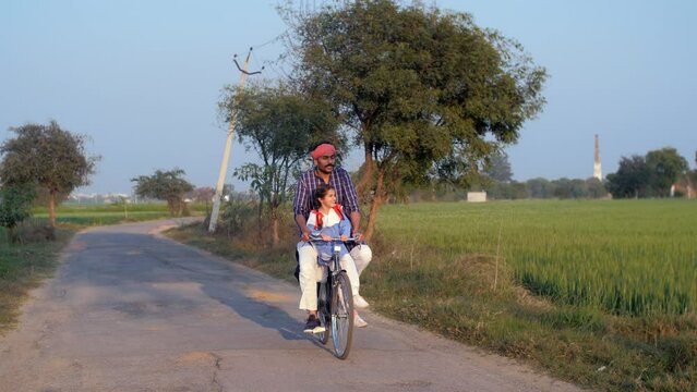 A happy little girl with braided hair is going to school with her brother in school uniform - village education  Literacy in rural India
. A middle-aged father wearing Kurta- Pajama is going to dr...