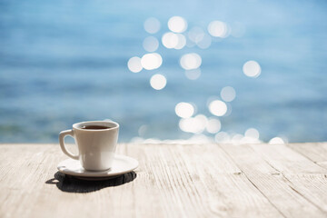 Coffee cup on wooden table over beautiful sea background. Travel background, vacations, summer fun,...