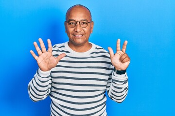Naklejka premium Middle age latin man wearing casual clothes and glasses showing and pointing up with fingers number eight while smiling confident and happy.