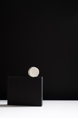 Queso cremoso de cabra sobre un soporte negro y fondo negro. Concepto minimalista