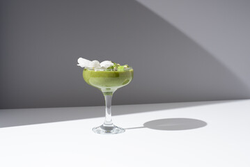 Batido de kiwi jugo de fruta saludable servido con trozos de kiwi en copa de cóctel sobre fondo...