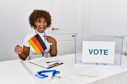 Young african american woman at political campaign election holding germany flag smiling happy pointing with hand and finger