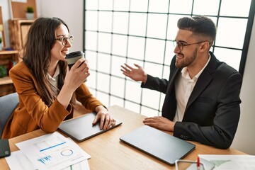 Two hispanic business workers smiling happy drinking coffee at the office.