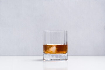 Un vaso de whisky sobre una mesa blanca y fondo claro