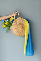 Ukrainian girl in a blue dress holds in a bag yellow and blue tulips