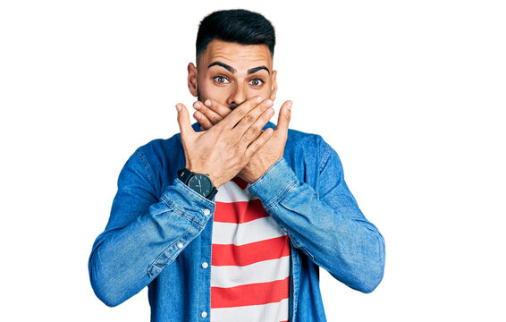 Young hispanic man with beard wearing casual denim jacket shocked covering mouth with hands for mistake. secret concept.