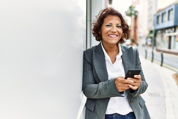 Middle age latin businesswoman smiling happy using smartphone at the city.