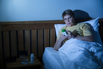 insomnia. Healthy sleep. elderly woman takes pills for insomnia sitting on bed at night