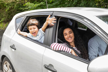 Glad young arabic man and woman driving car, little excited boy with open mouth gesturing, waving with hands at window
