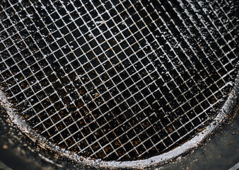 Background, texture, top view of a black round frying pan with a checkered pattern, after frying and cooking food, smeared with sunflower, olive oil. Photo of dirty dishes.