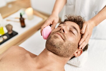Fototapeta na wymiar Young hispanic man having facial treatment at beauty center