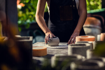 Obraz na płótnie Canvas Close up of craftswoman hands making decorative concrete vase in her workshop.