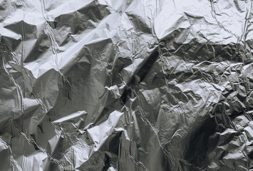 Background, texture of silver shiny foil, colored crumpled paper for packing goods. Close-up photo, top view, copy space.