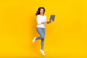 Photo of sweet adorable lady dressed white shirt jumping working modern device isolated yellow color background