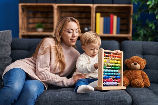Mother and son playing with abacus sitting on sofa at home