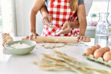 Couple hugging and kneading dough at the kitchen.