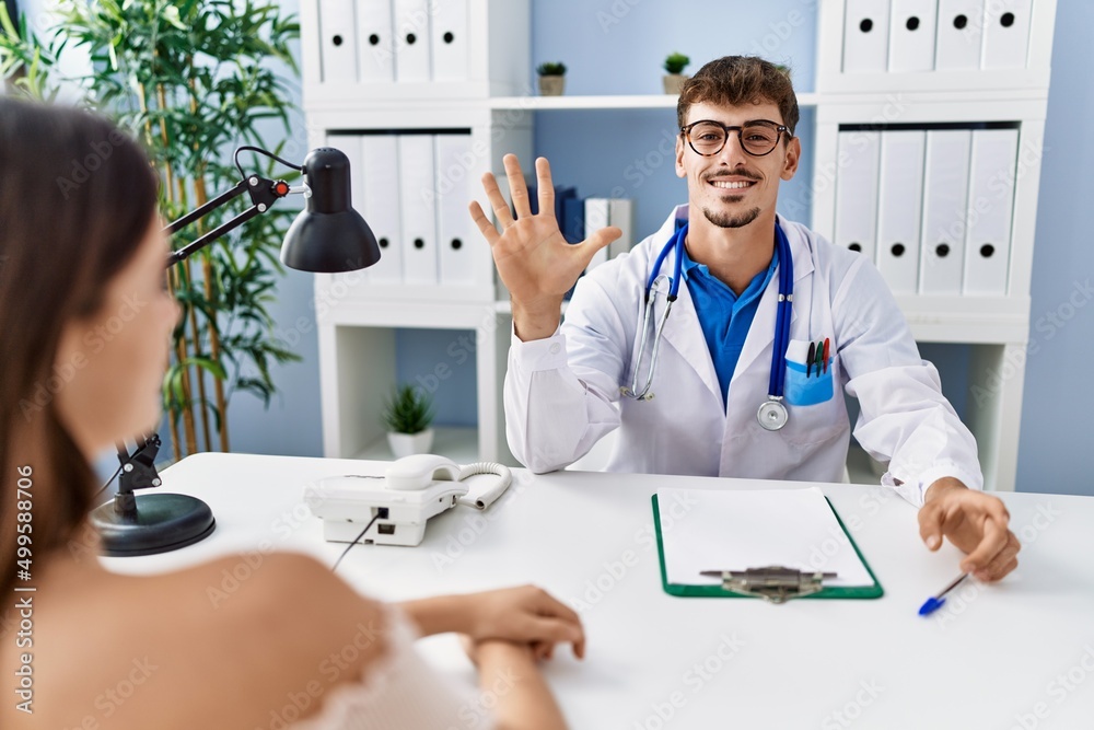 Sticker young doctor with client at medical clinic showing and pointing up with fingers number five while sm