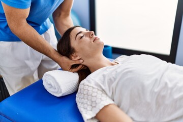 Man and woman wearing physiotherpy uniform having reiki therapy session at clinic - obrazy, fototapety, plakaty