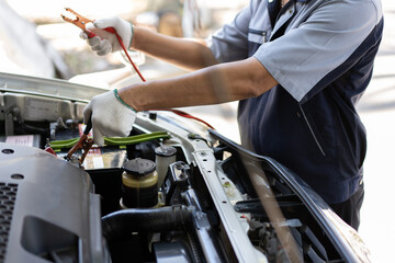 Close up and Selective focus of car mechanic holding battery electricity cables jumper for charging car battery, Services car engine machine concept