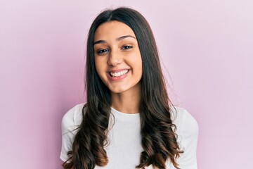 Young hispanic woman wearing casual white t shirt looking positive and happy standing and smiling with a confident smile showing teeth