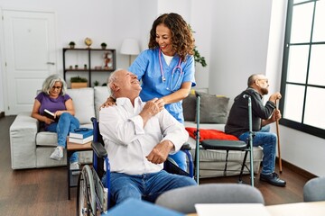 Fototapeta premium Middle age doctor woman supporting retired man sitting on wheelchair at nursing home.