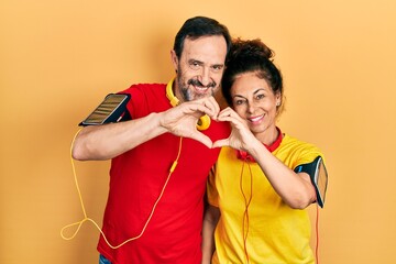 Middle age couple of hispanic woman and man wearing sportswear and arm band smiling in love doing...