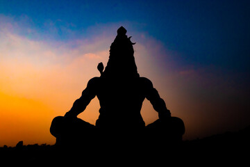 back lit statue of hindu god lord shiva in meditation posture with dramatic sky from unique angle - obrazy, fototapety, plakaty