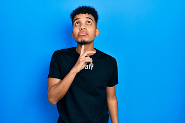 Young african american man wearing staff t shirt thinking concentrated about doubt with finger on...