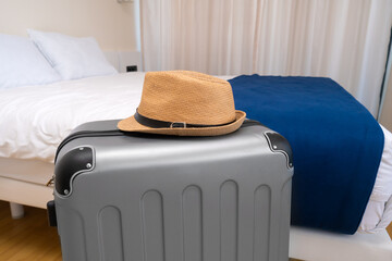 Close-up of a gray suitcase with a straw hat in a hotel room. Concept of travel, vacation