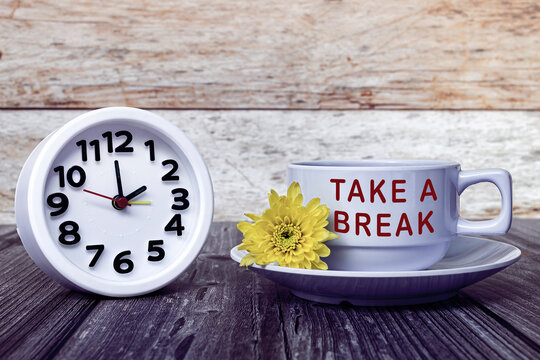 Take a break text written on white coffee cup with clock set at 2 o'clock.