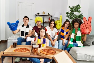 Group of young people wearing team scarf cheering football game thinking attitude and sober expression looking self confident