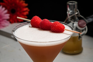 A French Martini cocktail garnished with fresh raspberries on a white background and styled with...