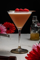 A French Martini cocktail garnished with fresh raspberries on a white background and styled with...