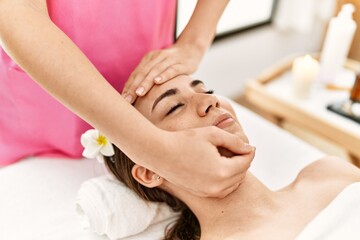 Fototapeta na wymiar Young hispanic woman smiling confident having facial massage at beauty center.